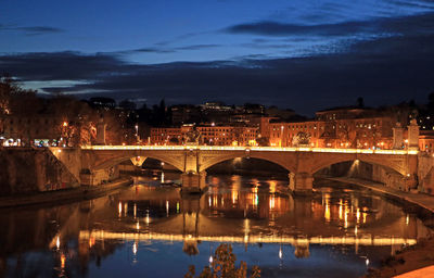 Illuminated bridge over river against sky at night