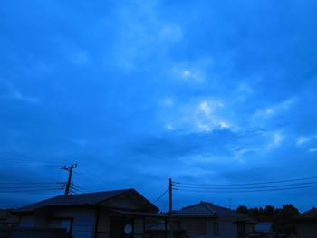 Low angle view of silhouette buildings against blue sky