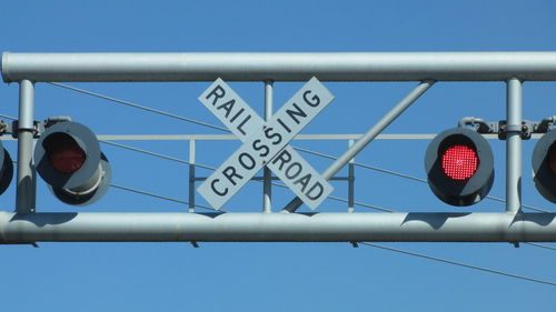 Low angle view of stoplight and road sign against blue sky