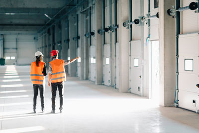 Rear view of architect discussing with coworker at site