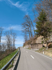 Empty road amidst trees against sky