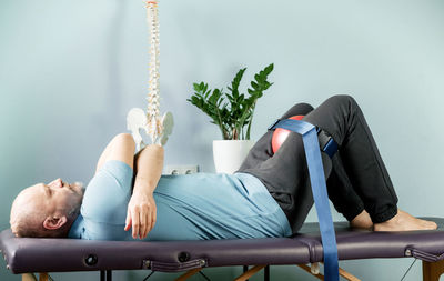 A man lying on the massage table in constructive rest postion with foam roller and malligan belt