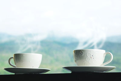 Close-up of coffee on railing against mountains