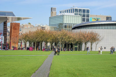 People in park by buildings against sky