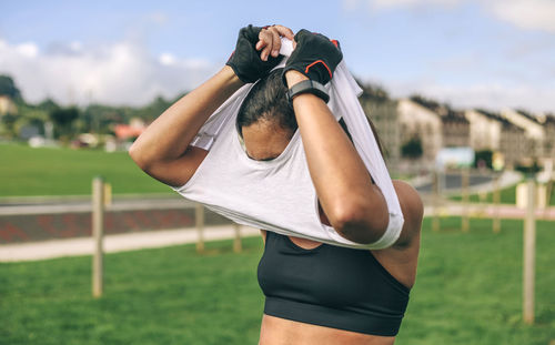 Sportswoman taking off t-shirt at park