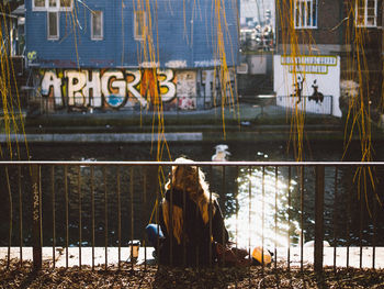 Rear view of woman sitting by canal