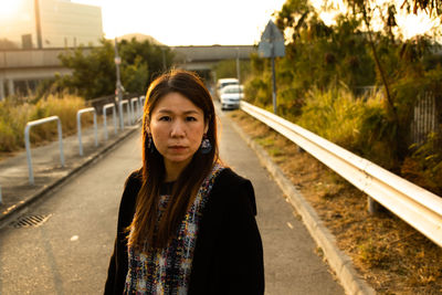 Portrait of young woman standing on road