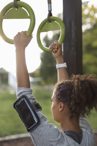 Woman hanging on gymnastic rings at park