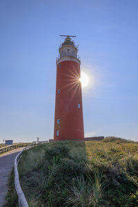 Lighthouse by sea against sky during sunset