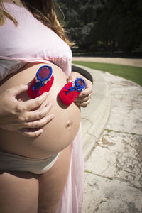 Seven months pregnant woman with red and blue booties on her belly