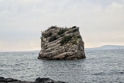 Rock formation in sea against sky