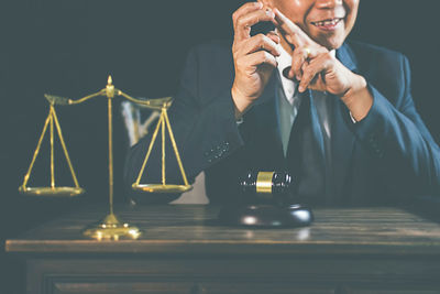 Midsection of man using mobile phone while sitting on table