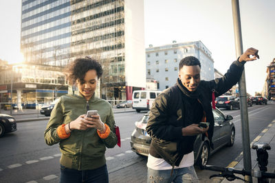 Full length of friends standing on street in city