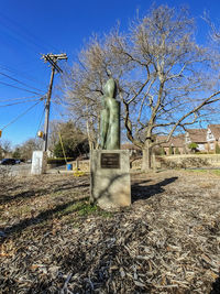 Statue of bare tree in field against clear sky