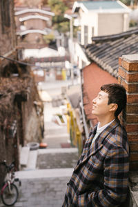Side view of man standing on street against buildings