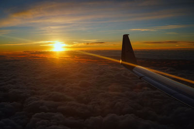 Airplane wing against sky during sunset