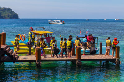 People standing on boats in sea against sky