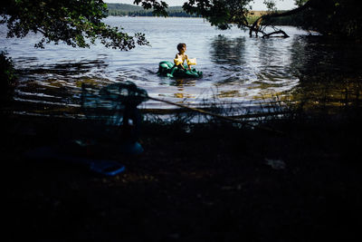 Reflection of man sitting in lake