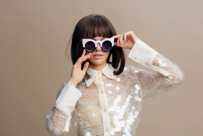 Portrait of woman wearing sunglasses against white background