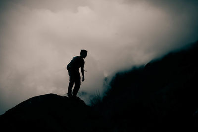 Low angle view of silhouette man on mountain against sky