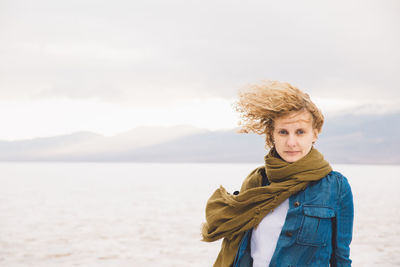 Portrait of young woman standing at death valley national park against cloudy sky