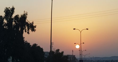 Silhouette trees and street against sky during sunset