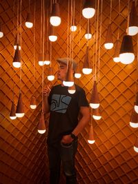 Man standing by illuminated pendant lights