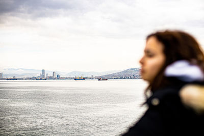 Pensive young girl looking to sea from boat. teenager girl at ferryboat. cold grey sea