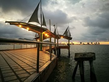 Pier on sea against sky at sunset