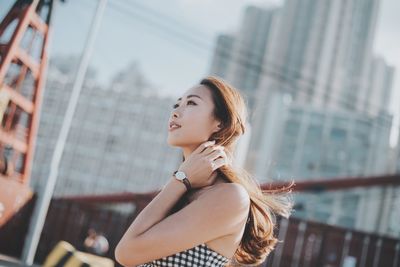 Side view of beautiful woman looking away in city