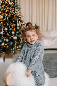 Smiling little girl child in a sweater having fun and laughing holding gift box on christmas holiday