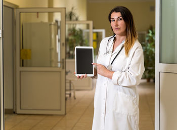 Young woman using phone while standing in corridor
