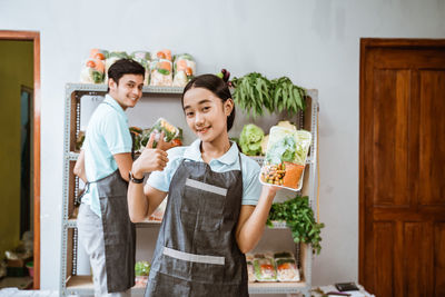 Portrait of smiling young woman standing in kitchen