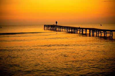 Pier over sea against sky during sunset