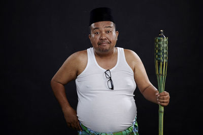 Portrait of smiling man standing against black background