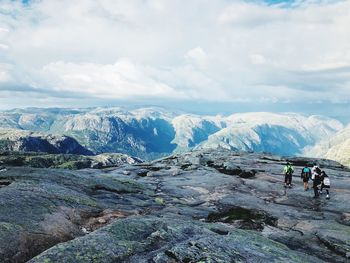 People on rocks against mountain range and sky