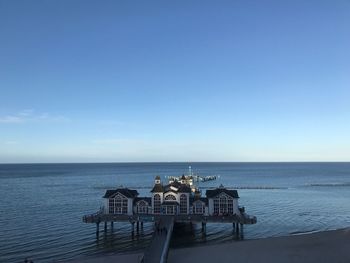 People on table by sea against blue sky