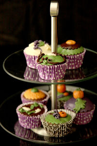 Close-up of halloween cupcakes on cakestand against black background