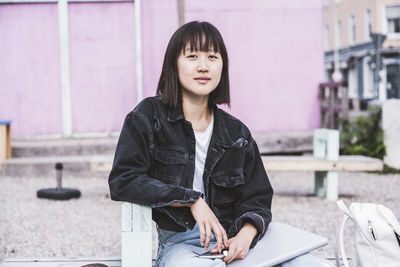 Female teenager with laptop sitting on bench