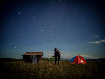 Rear view of men standing on field against sky at night