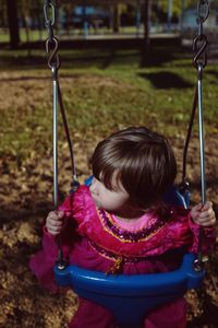 Girl in pink dress on swing at park
