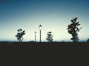 Low angle view of silhouette trees against blue sky