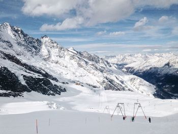 Scenic view of snow covered mountains against cloudy sky
