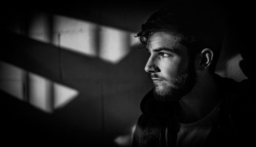 Close-up of young man looking away against wall