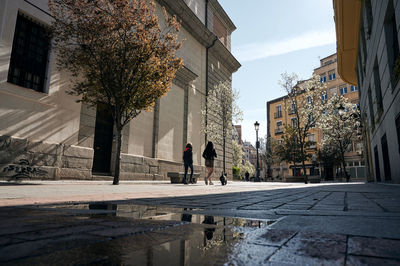 People walking on street amidst buildings during rainy season