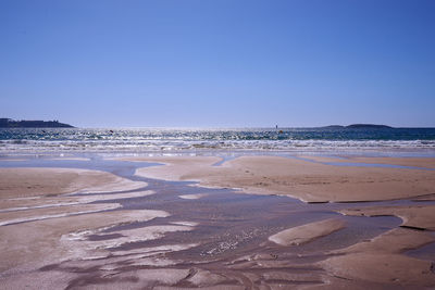 Scenic view of beach against clear blue sky