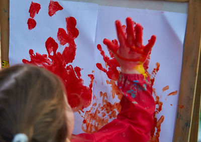 Girl painting with red paint on papers