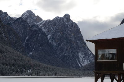 Stilt house over snowy field against snowcapped mountains