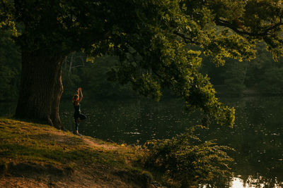 Side view of woman exercising by lake