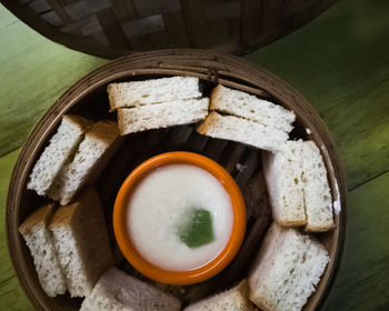 Steam thai sangkaya or pandan kaya bread with sweet dipping served in a traditional bamboo steamer.